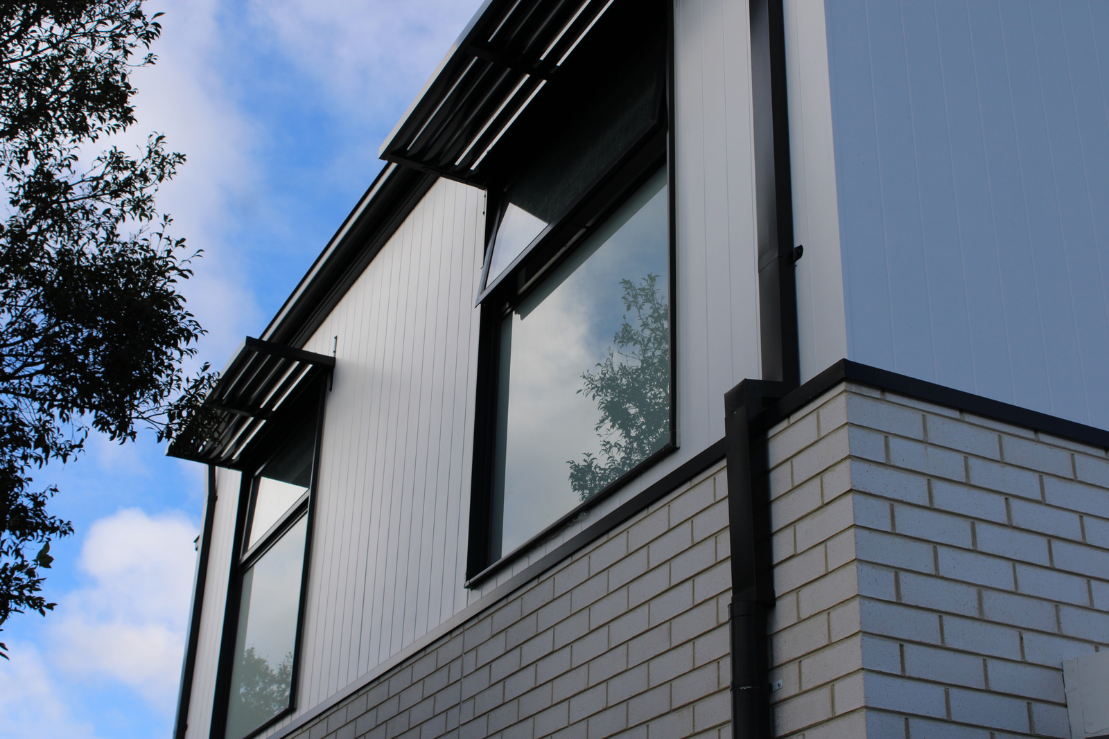 James Hardie Axon cladding aligned around a tall window and meeting recycled brickwork