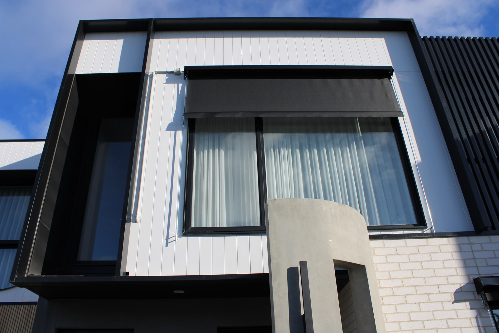 Deep black 250 by 50 millimetre aluminium battens forming a custom border around a facade window