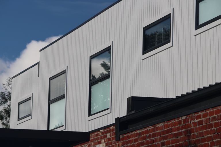 White James Hardie Axon cladding with black framed windows and brick base