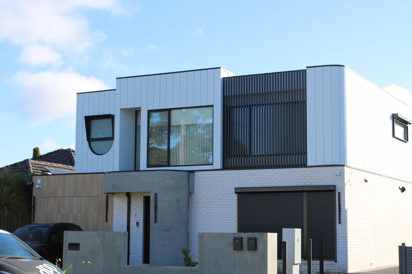 Finished Melbourne townhouse facade by CLADSMAN — white vertical panel cladding with black batten screen and timber-look details