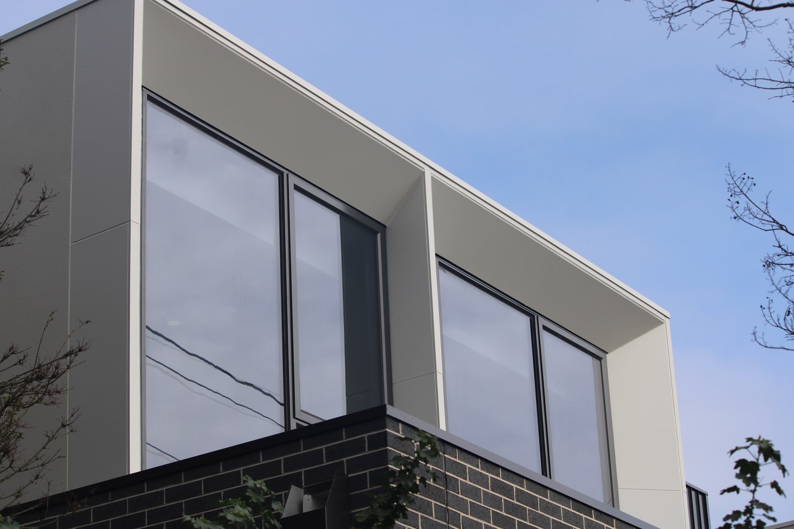 James Hardie Matrix cladding around tall windows with clean expressed joints and black brick below