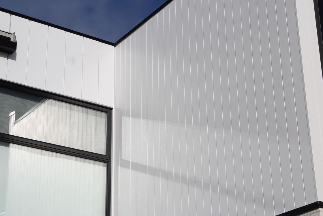 Close view of white Axon cladding meeting a black window frame with crisp vertical lines