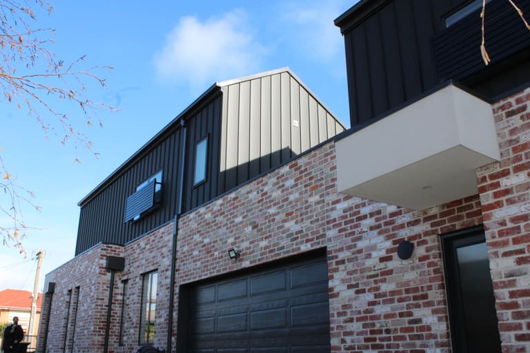 Black and white panels over recycled brick facade