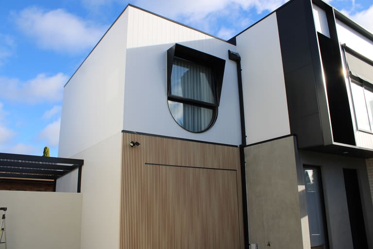 Round window detail in white vertical panel over timber-look slats