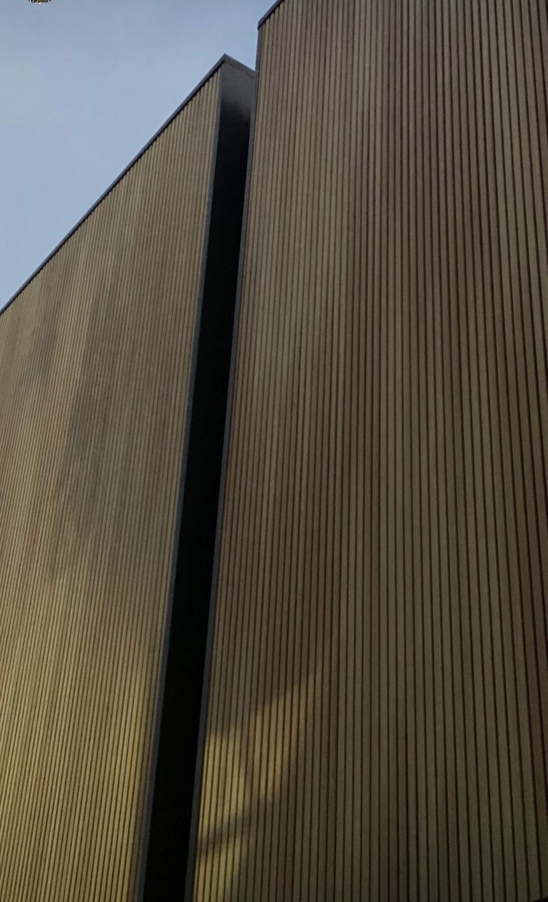 NewTechWood Castellation Cladding in Cedar installed vertically with a black recessed junction