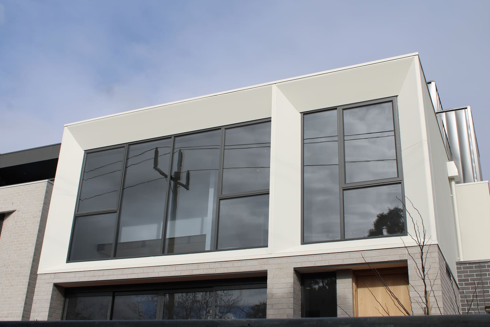 Crisp white panel window surrounds framing large glazing on a modern Melbourne townhouse